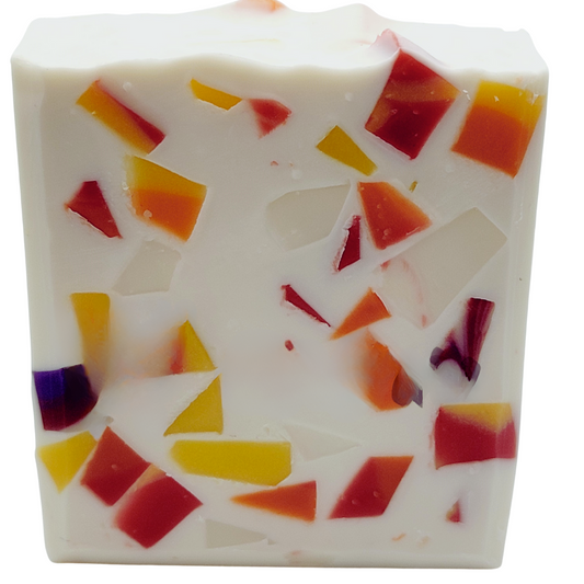A white soap with mosaic pieces of soap in reds, yellows, purples and oranges.