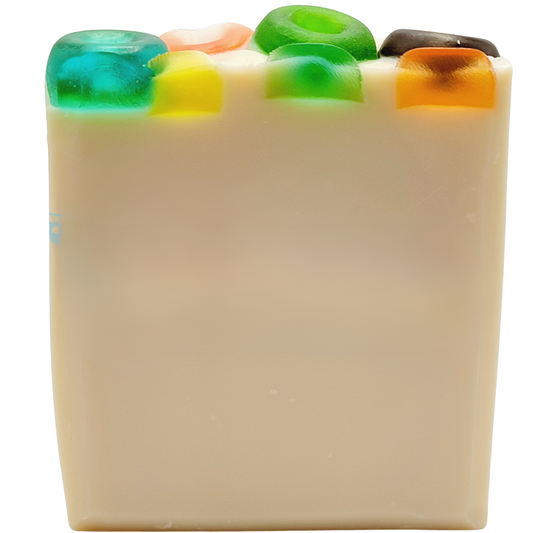 A white bar of soap topped with fruit loop shaped and colored melt & pour soap