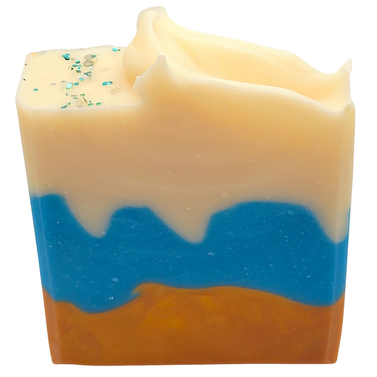 An ocean landscape inspired soap with tan on the bottom, blue in the center and white on the top. With a touch of blue biodegradable glitter on the top.