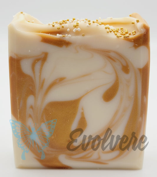 White and gold/tan swirled soap with textured top, topped with white and gold jojoba beads