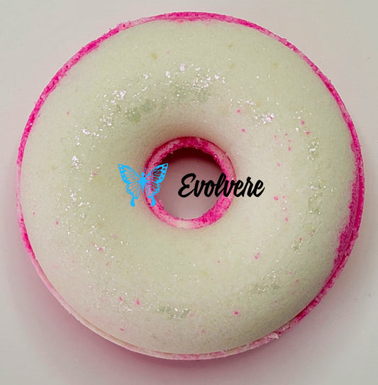 A hot pink and white donut shaped bath bomb dusted with an iridescent mica.